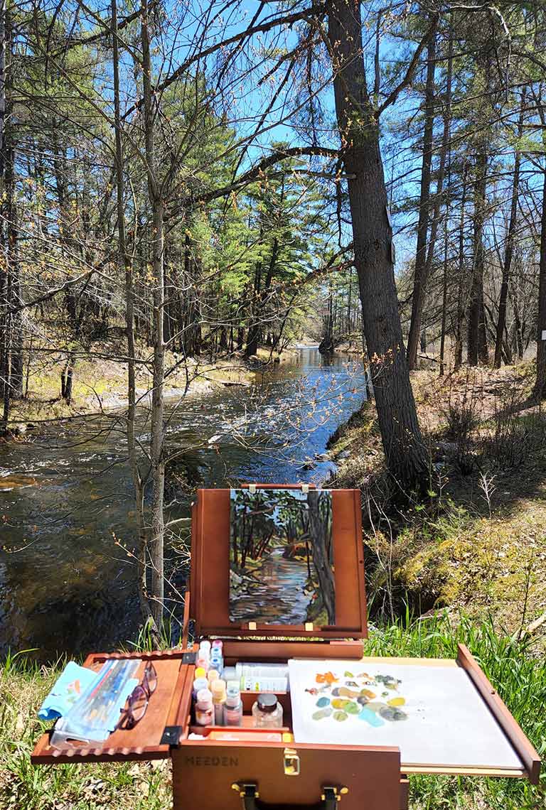 Studio 201 artist's easel, paints and canvas overlooking a woodland stream in early Spring